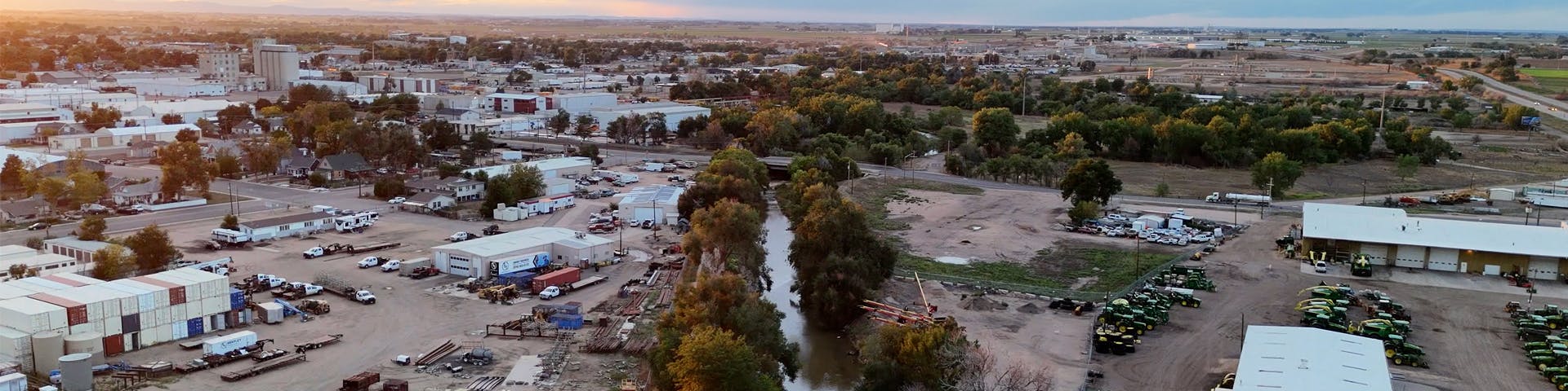 Aerial perspective of the Poudre River with industrial lots and farm equipment on either side of the river. 