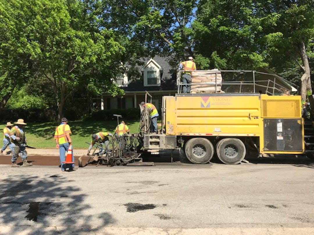 Street maintenance crew makes repairs on asphalt street.