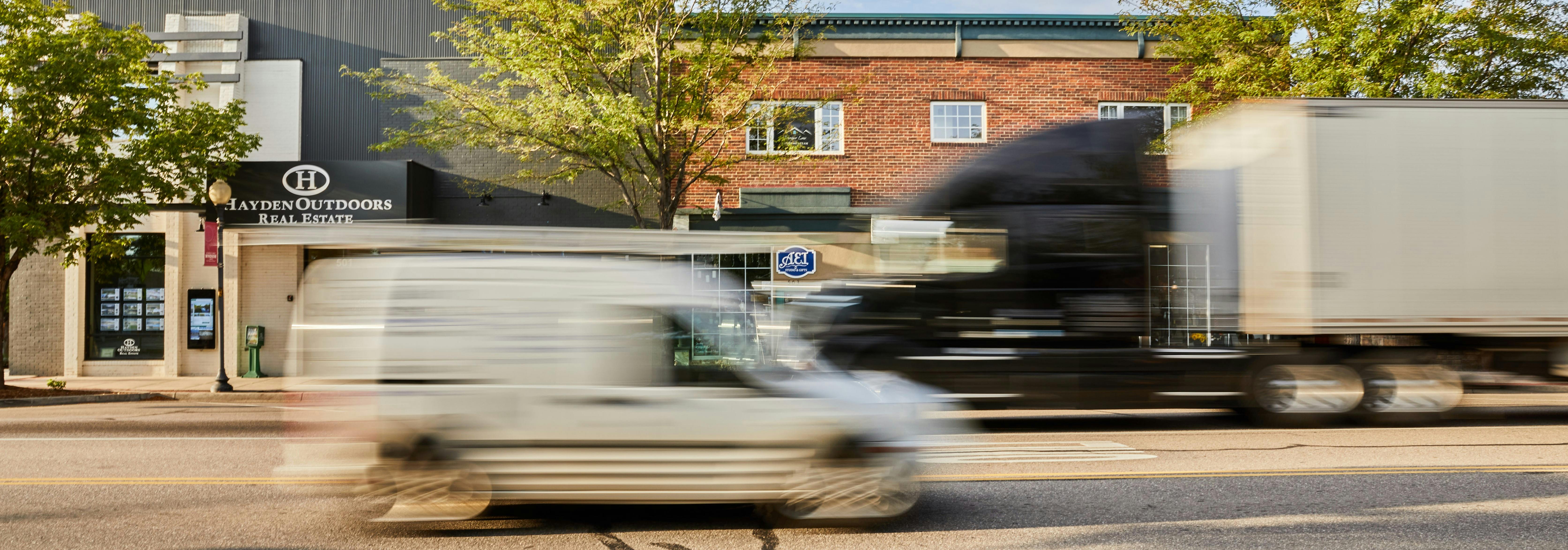 Truck and van crossing in front of shops in Downtown Windsor