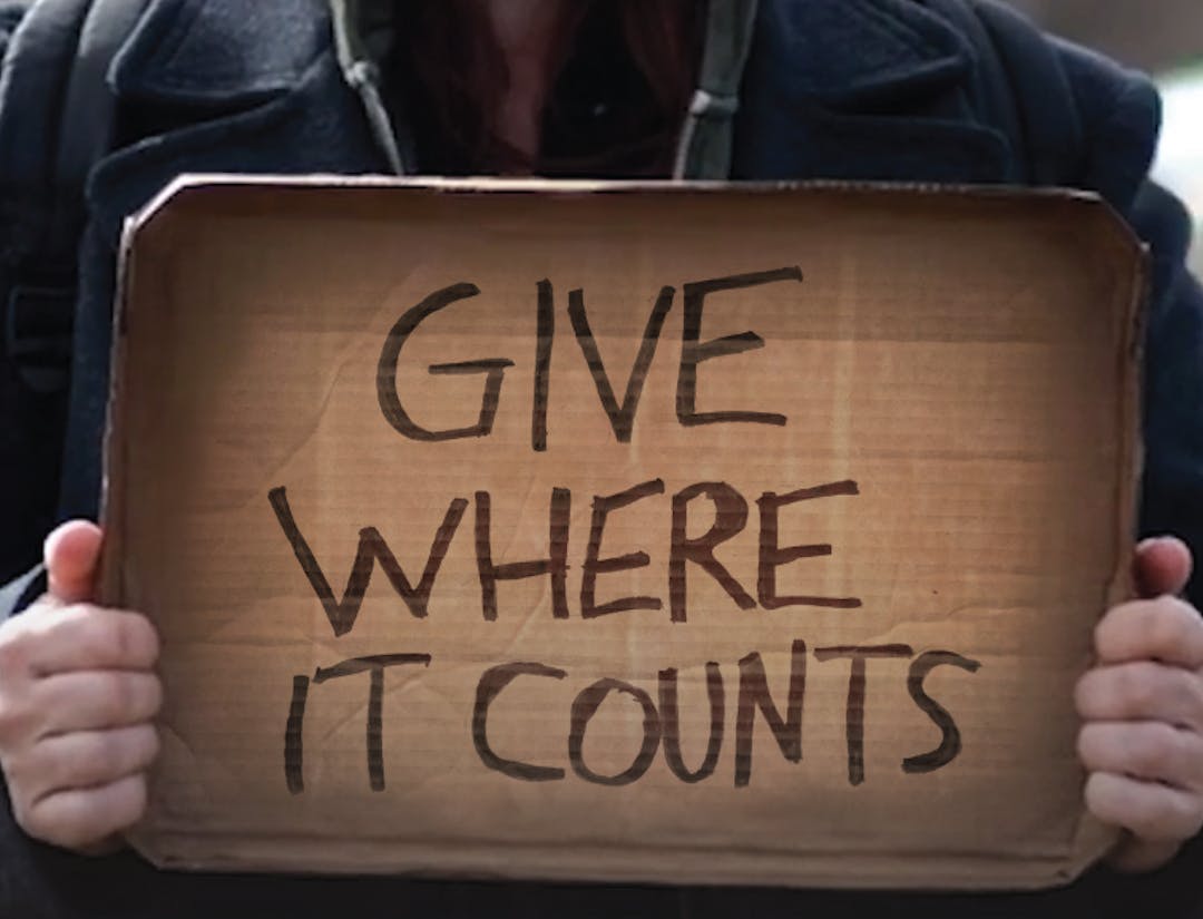 Panhandler holding a sign saying change the way you give