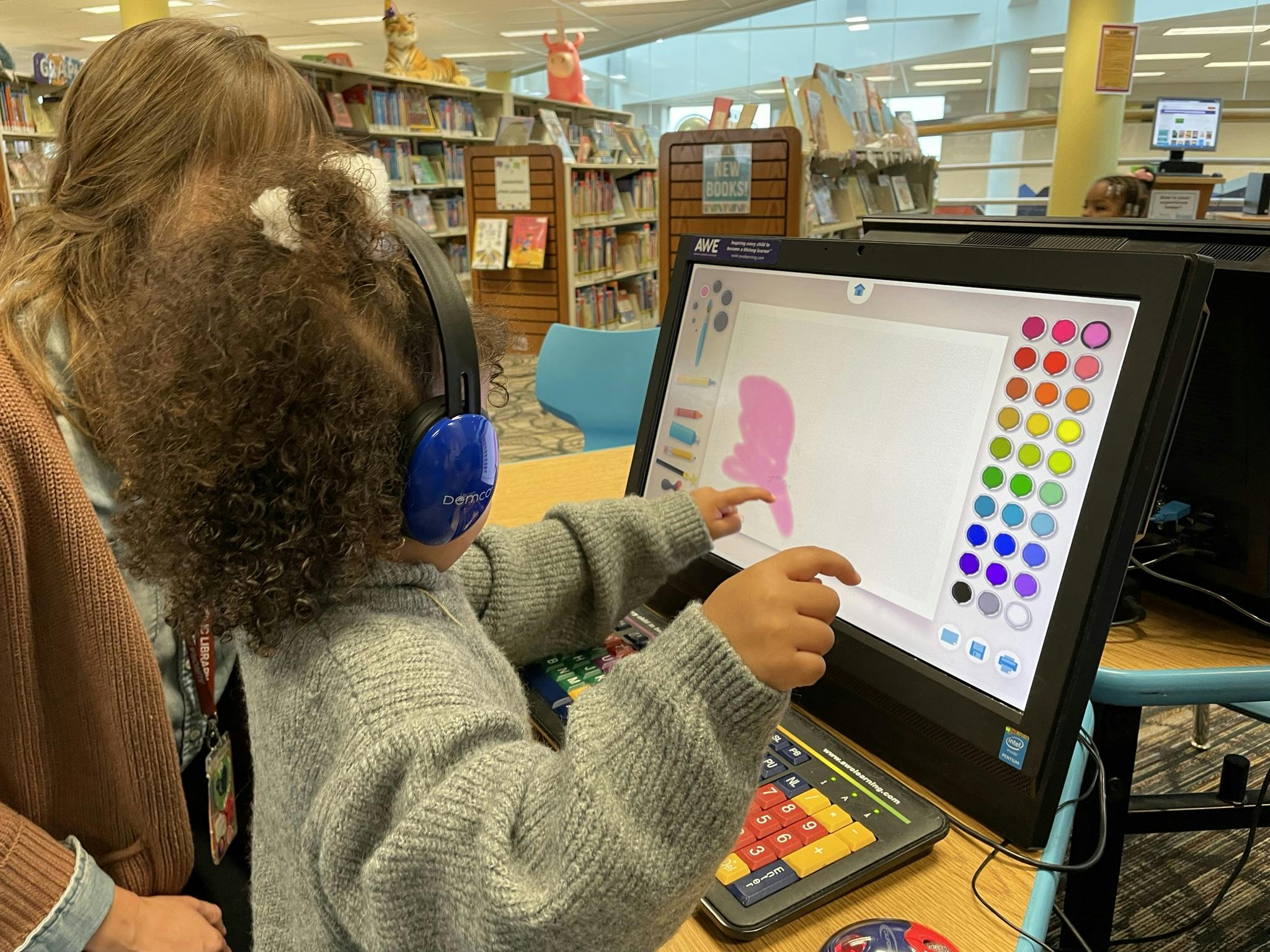 Library staff helping a child interact with a computer