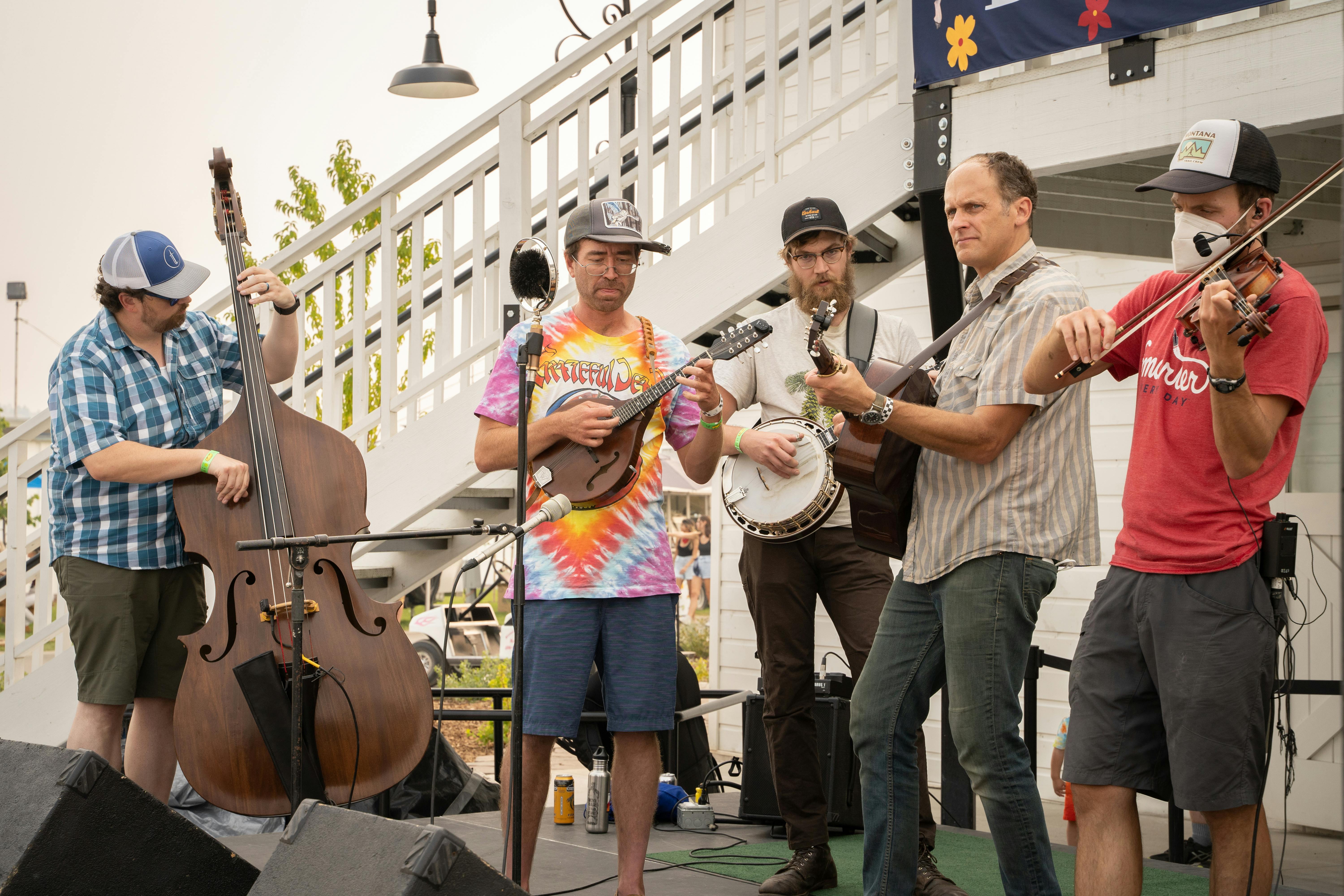 A string band with a bass, mandolin, banjo, guitar and fiddle playing at the Fair on a sunny day.