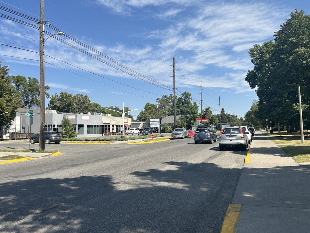 Businesses at the intersection of 9th and College with cars parked on the street