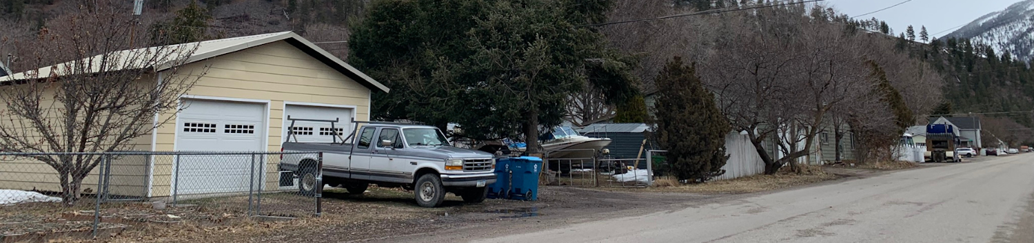 View along West Riverside Drive with truck and garage on spring day