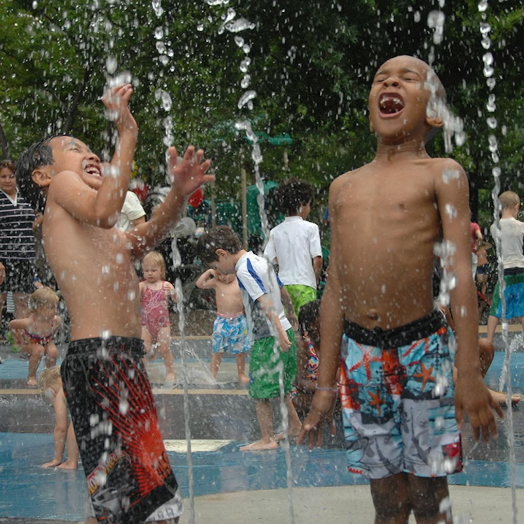 Two children  playing with water sprays at a splash water park
