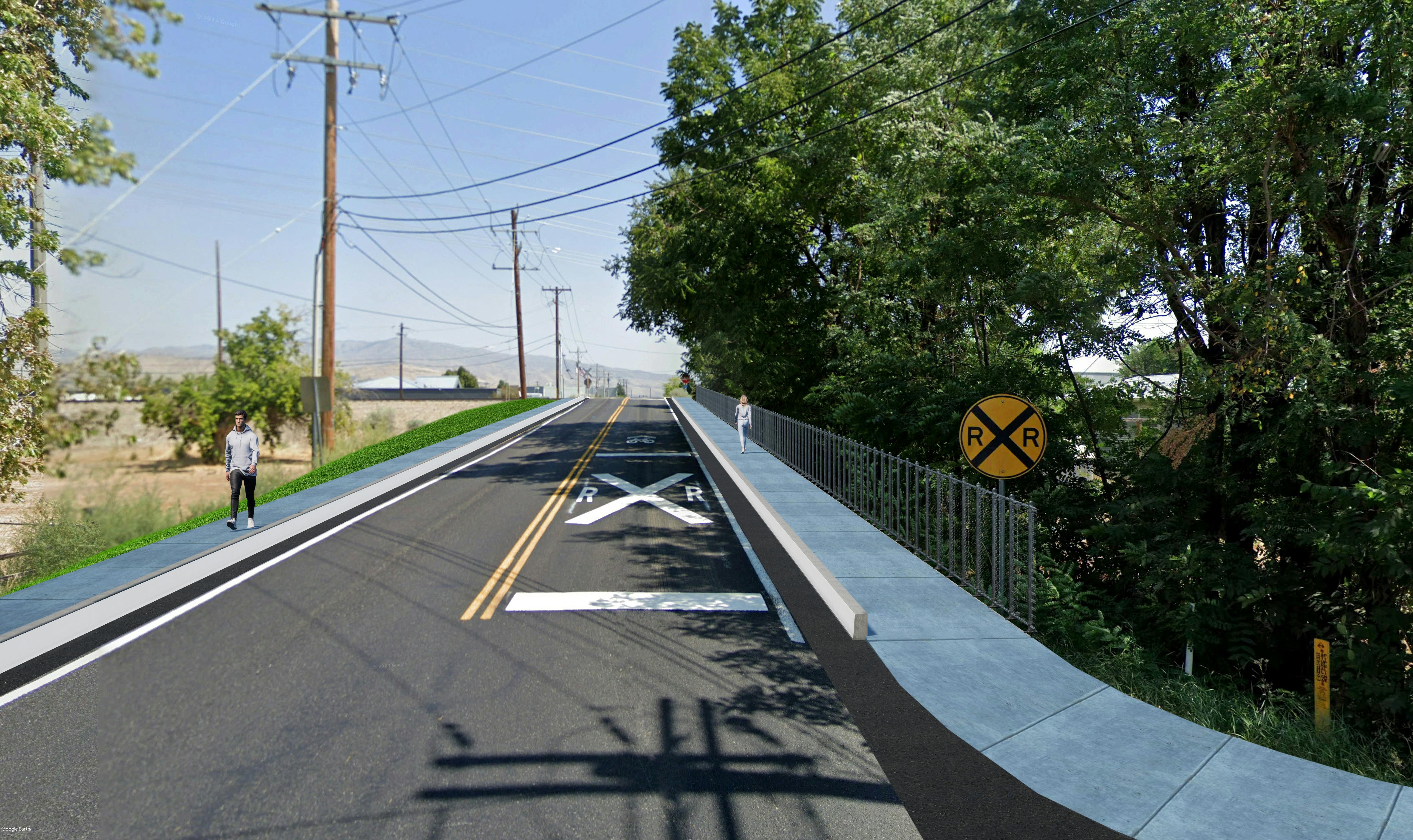 Victory Road coming up to the railroad crossing with sidewalks on both sides and a pedestrian railing.