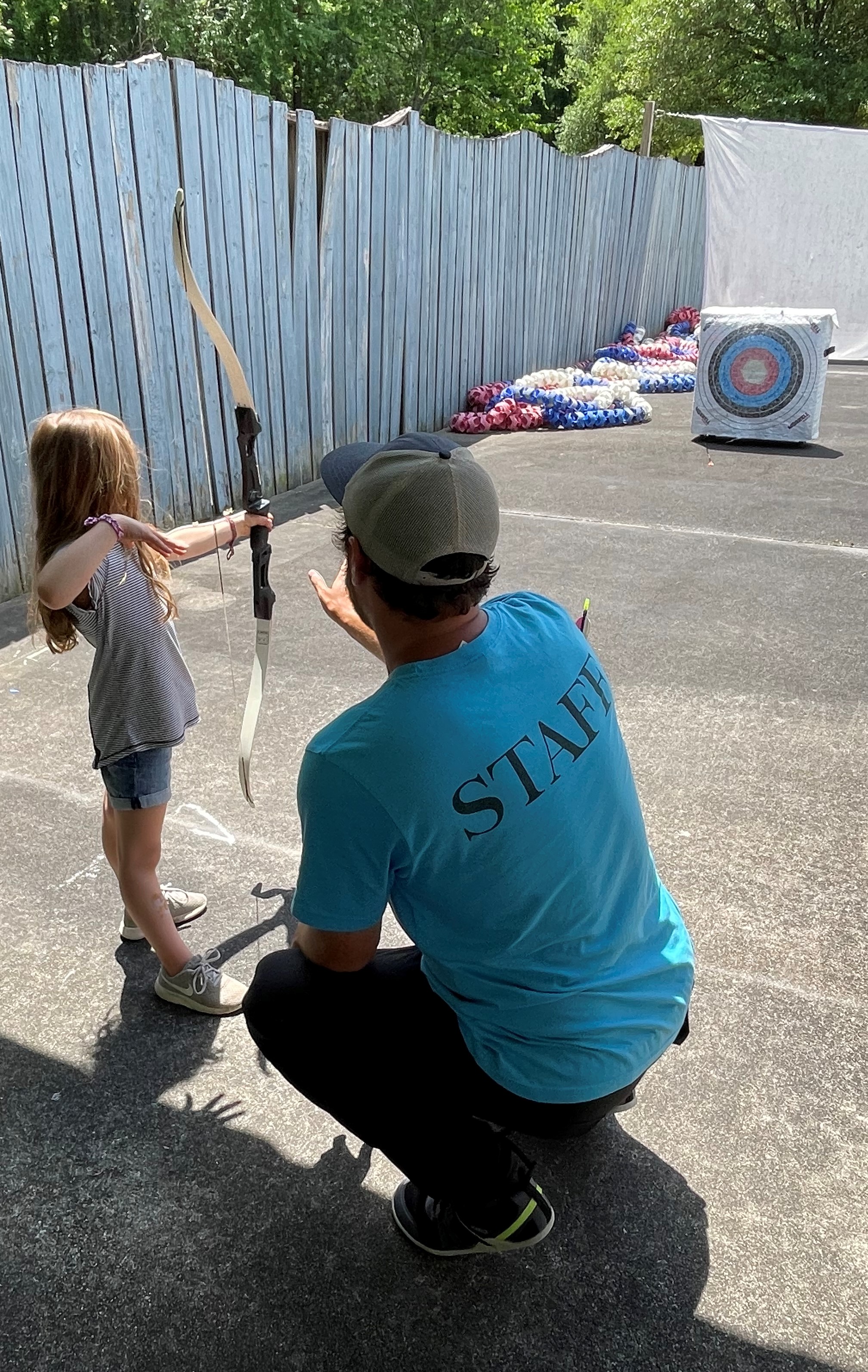 Photo of a girl with a bow and arrow, guided by Parks and rec staff