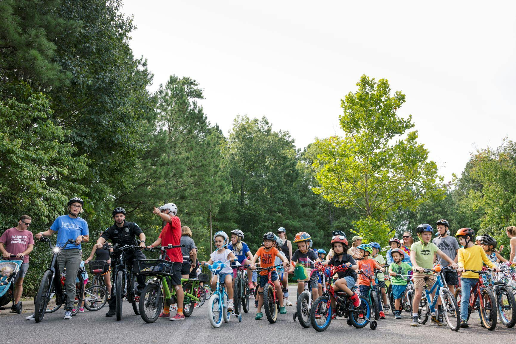a group of kids and adults on bikes and scooters about to start a parade