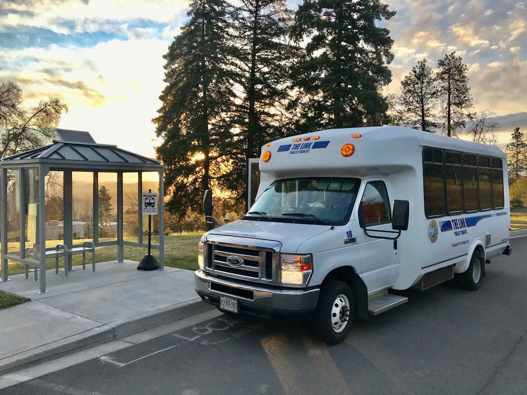 bus at bus stop with sunset behind it