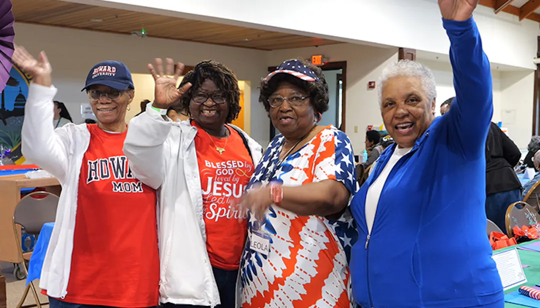 Four elderly woman at the Older American's Month celebration waving at the camera