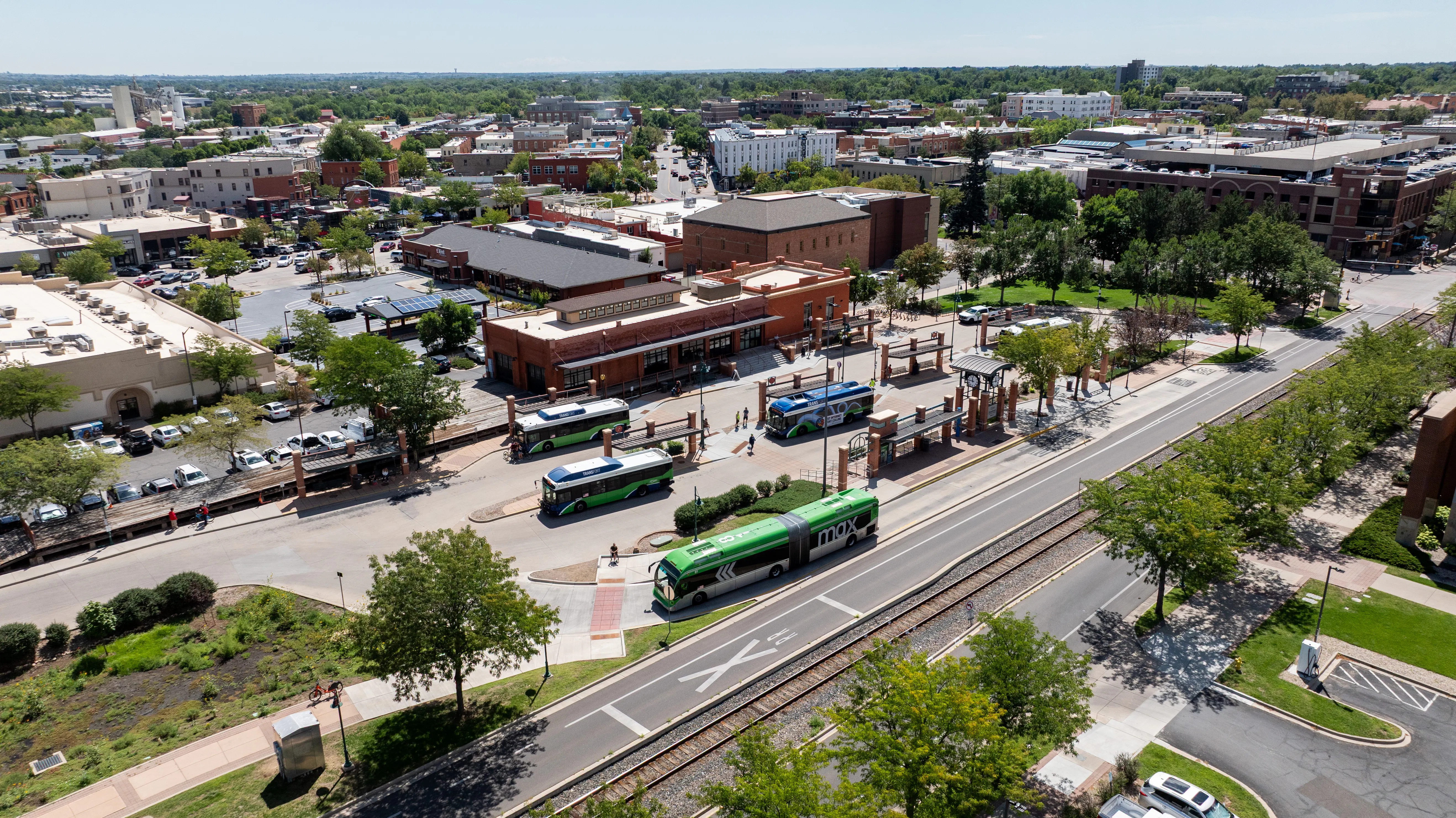 An aerial view of a transit center with buses parked and people and traffic moving. 