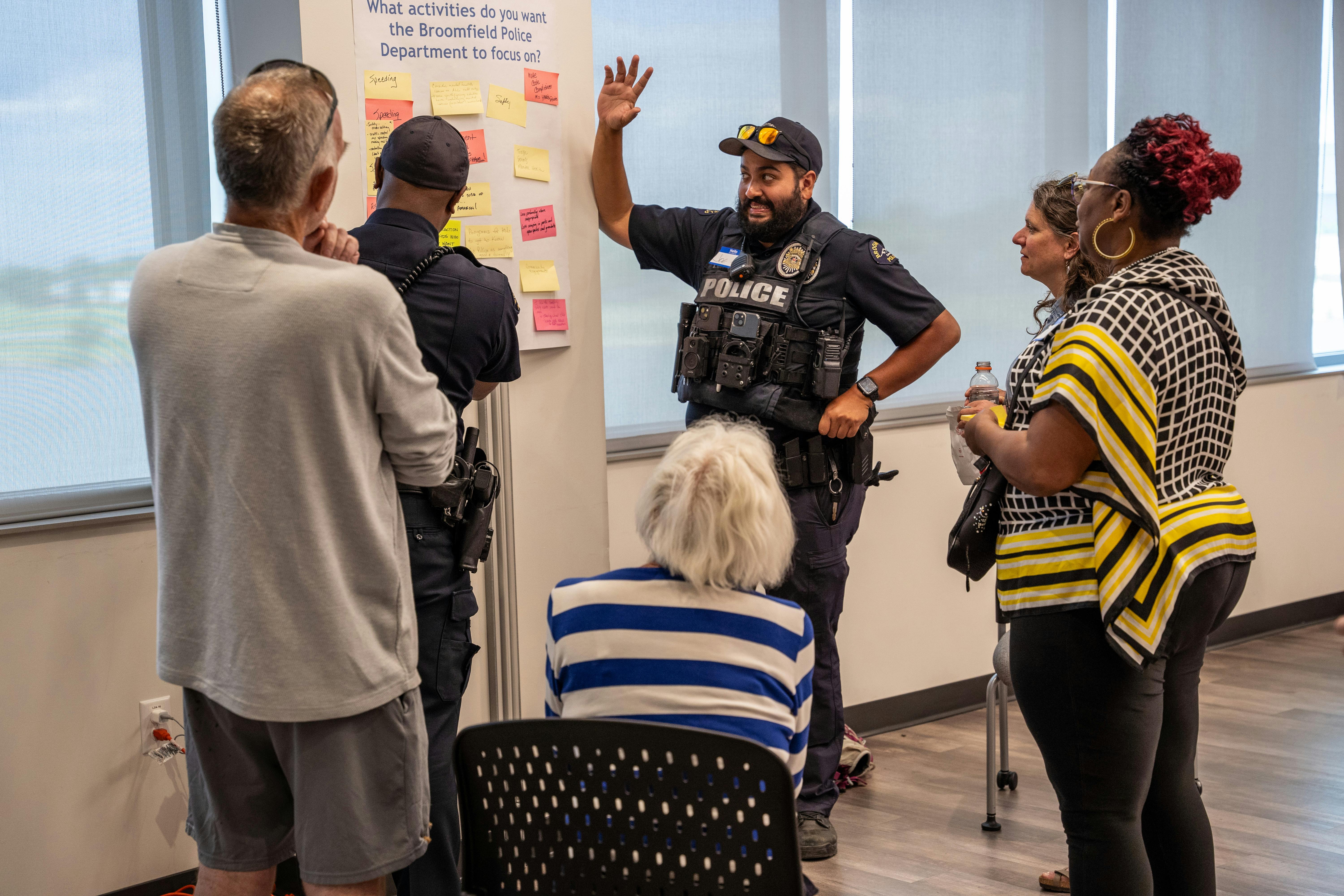 A group of participants gathers around a poster while a police officer points to sticky notes that the group posted